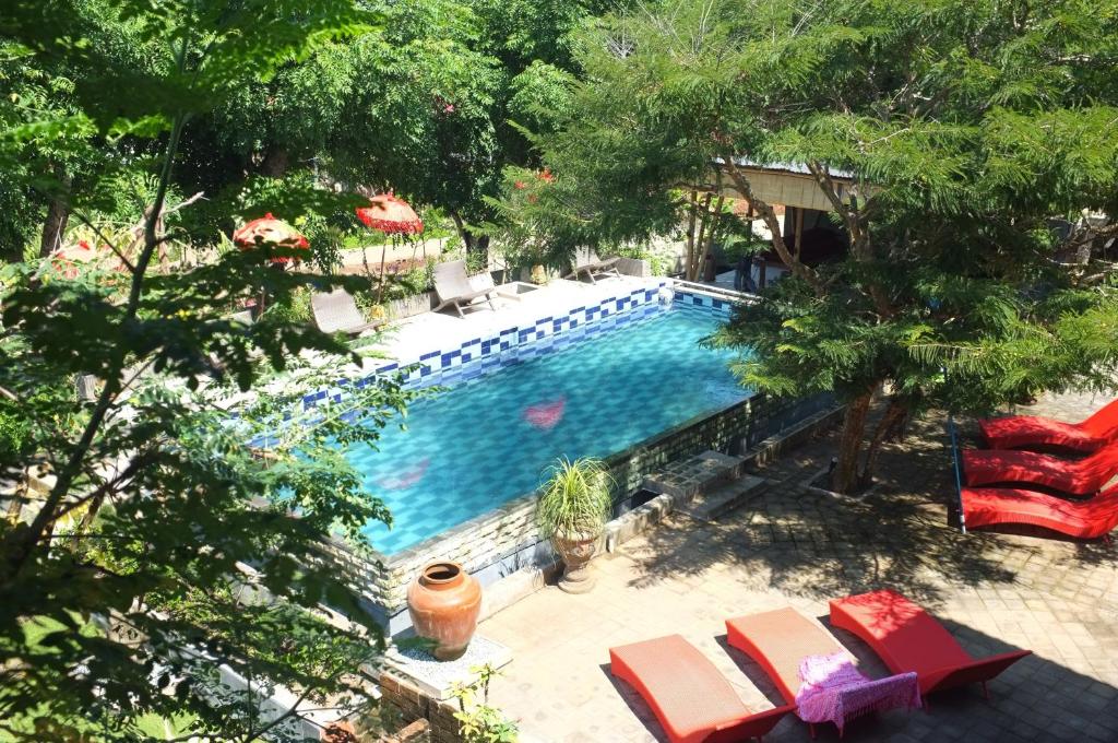 einen Blick über einen Pool mit Stühlen und Bäumen in der Unterkunft Villa Anjing 2 in Nusa Dua