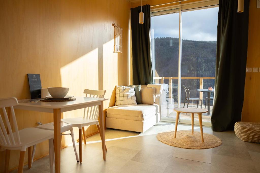 ein Wohnzimmer mit einem Tisch, einem Sofa und einem Fenster in der Unterkunft Casa Raposa Lodges - Terrace Mountain View in Manteigas