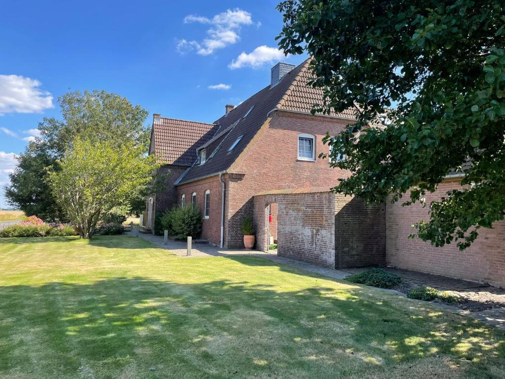 a brick house with a lawn in front of it at Pension Nordwind in Hedwigenkoog