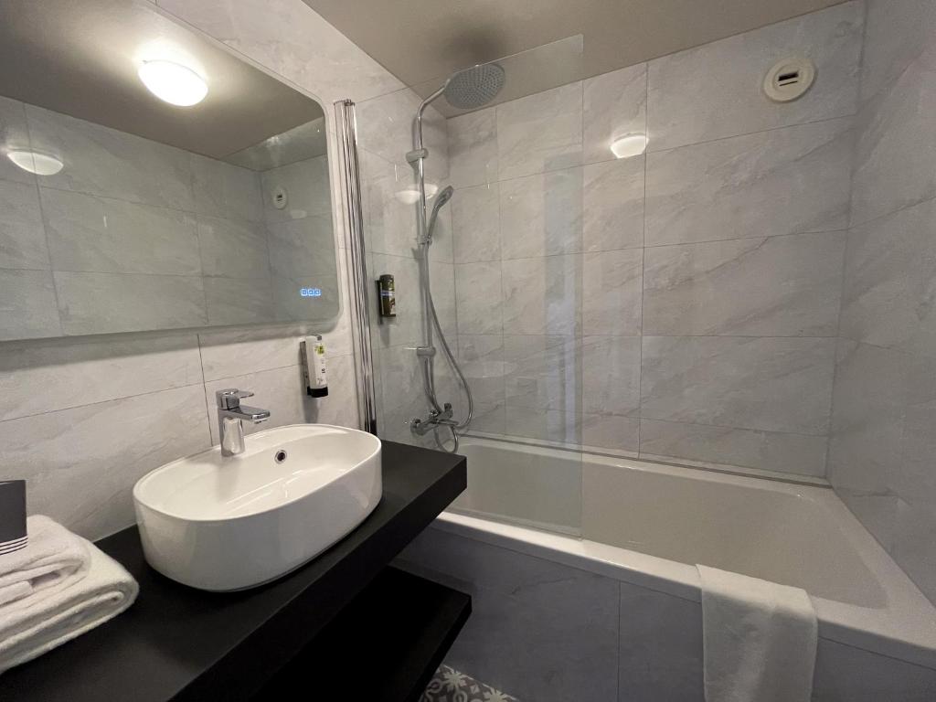 a bathroom with a sink and a shower and a tub at Hôtel Arcadia in Lannion