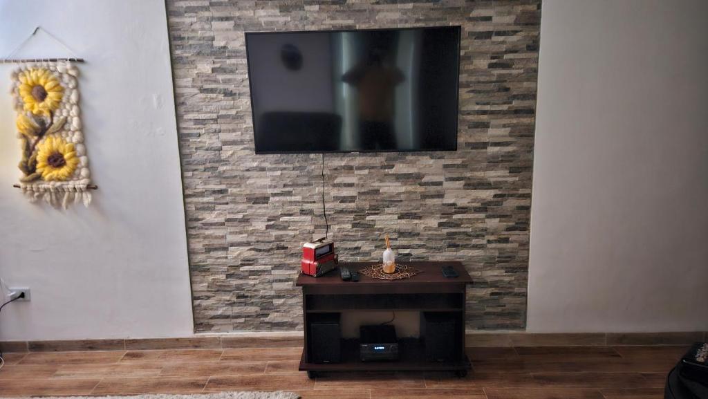 a living room with a tv on a brick wall at Departamento con Piscina y Estacionamiento in Chillán
