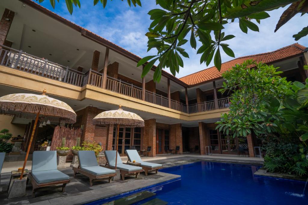 a resort with a pool and chairs and umbrellas at Wiras Village in Canggu