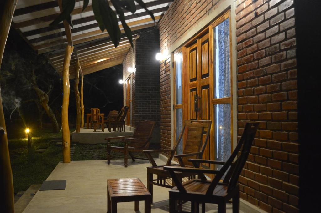 - une terrasse avec des chaises et une porte en bois la nuit dans l'établissement WILAPTTU WILD VILLA, à Pahala Maragahawewa