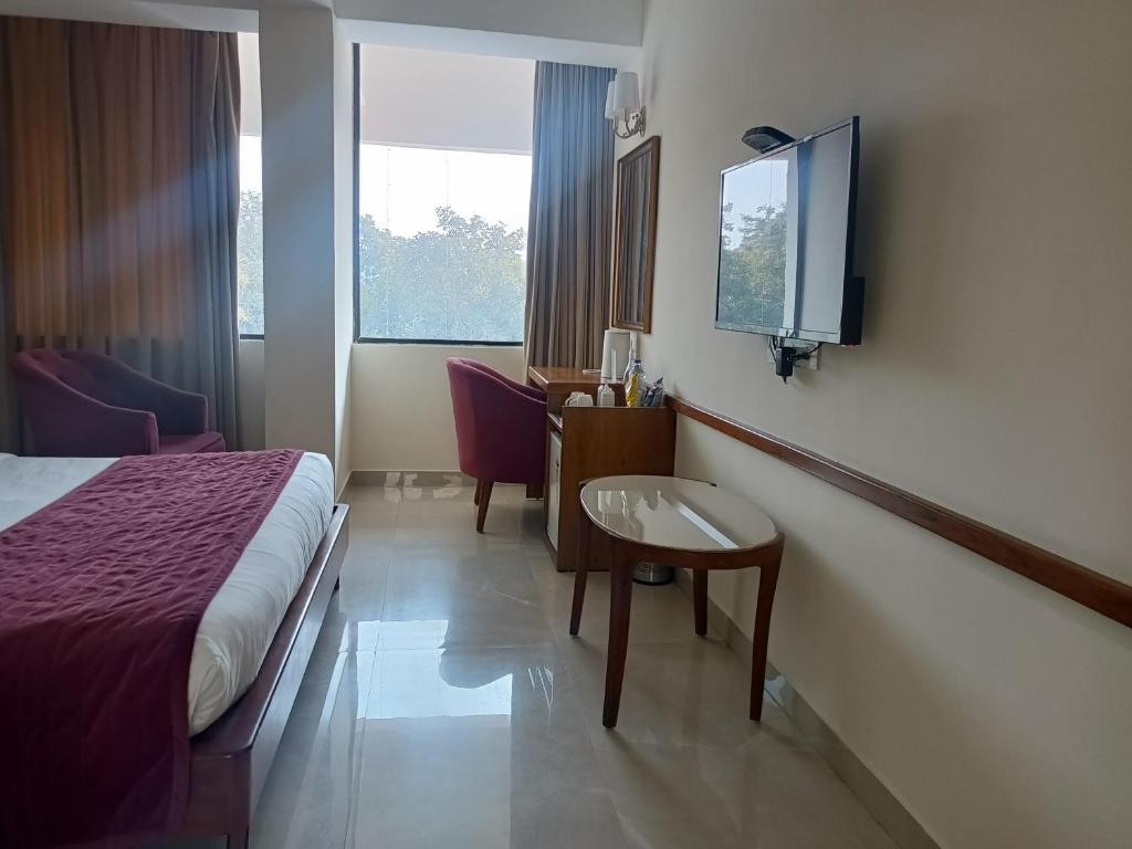 um quarto de hotel com uma cama e uma mesa e uma televisão em zoz Chandigarh em Chandīgarh