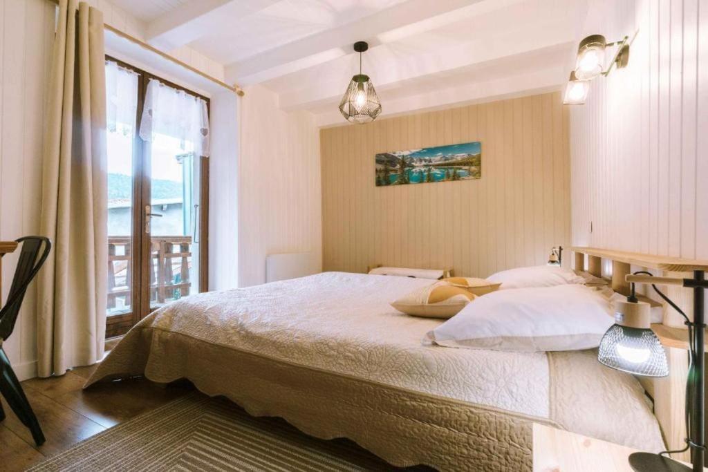 a bedroom with a large bed and a large window at La Petite Maison in Bonvillard