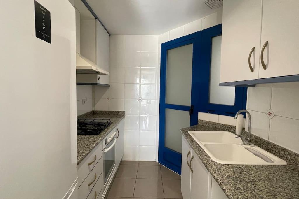 a white kitchen with a sink and a stove at Apto. luminoso con vistas en playa de La Patacona in Valencia