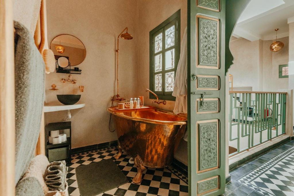 baño con bañera de madera y ventana en Le Petit Kenzara & magical rooftop en Marrakech