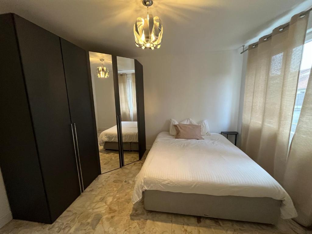 een slaapkamer met een bed met een spiegel en een kroonluchter bij Loge zen in Châteauroux