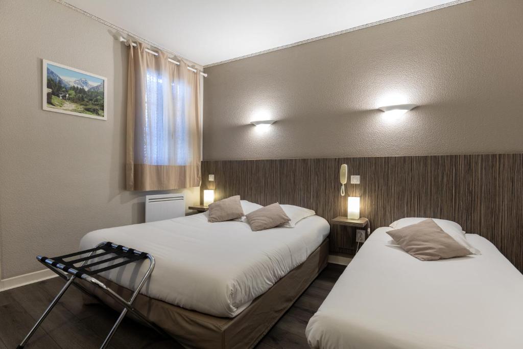 2 łóżka w pokoju hotelowym z 2 łóżkami w obiekcie Hôtel Café les Fleurs w mieście Argelès-Gazost