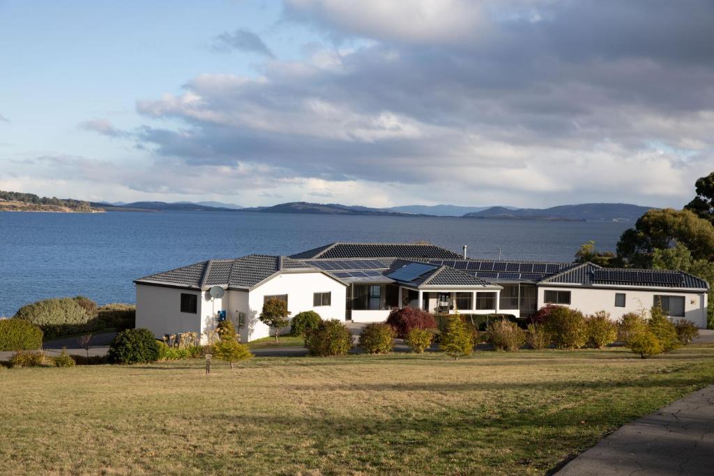 a house with solar panels on it next to the water at Sea View Guest House in Hobart