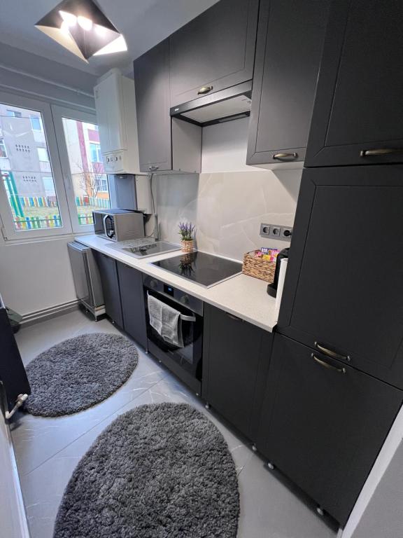 une cuisine avec des armoires noires et deux tapis dans l'établissement Britannia ShortStay Apartment Caransebes, à Caransebeş