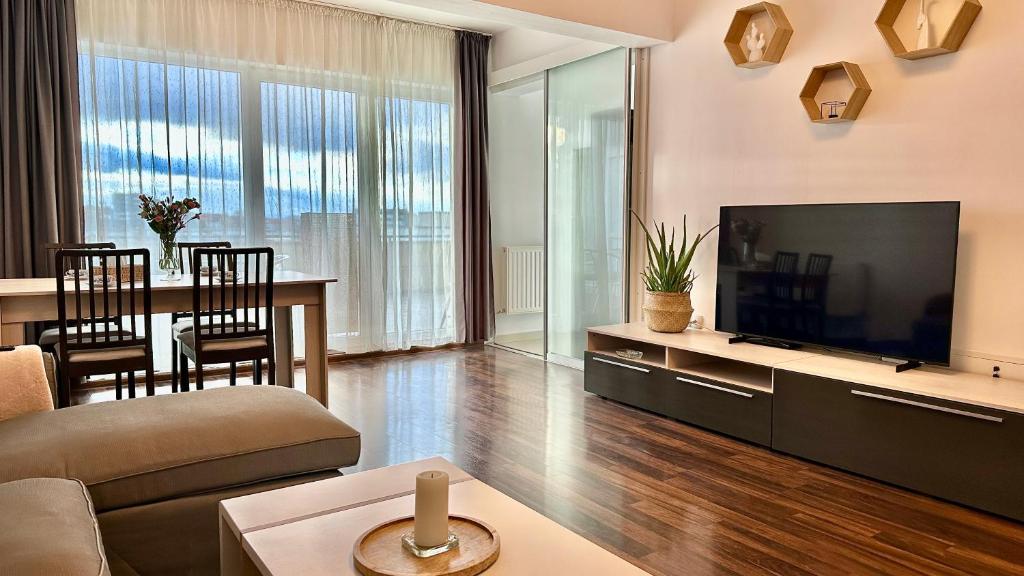 a living room with a large television and a table at Bonjour Residence with terrace and parking in Cluj-Napoca