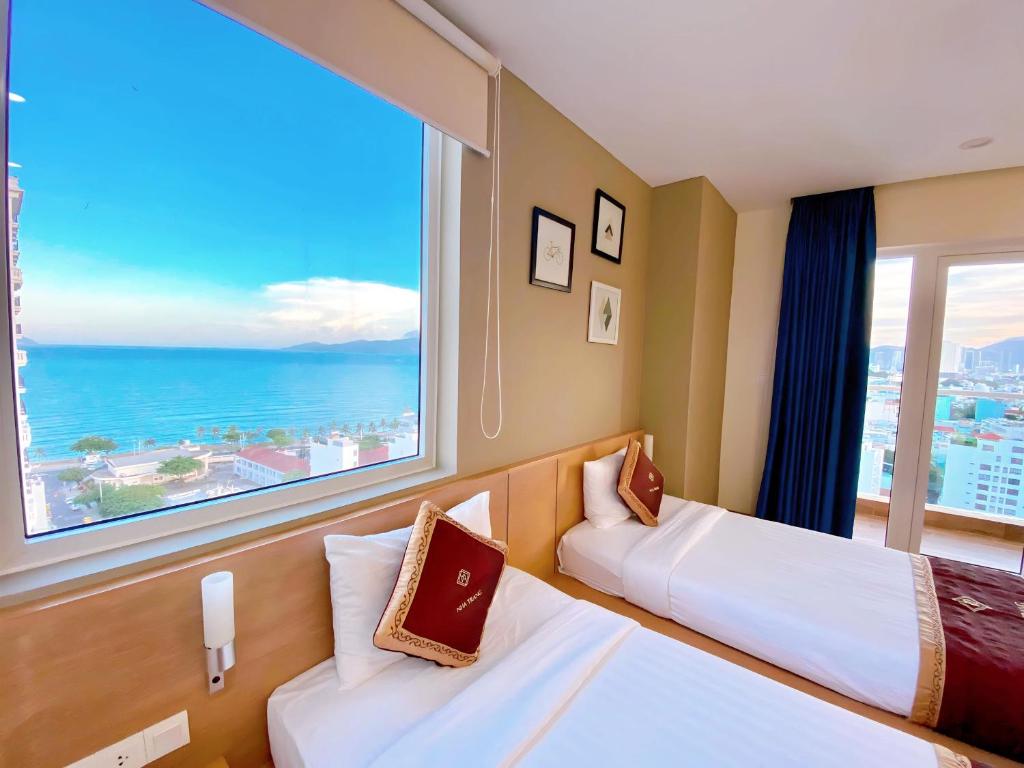 a hotel room with two beds and a large window at Gibson Hotel Nha Trang in Nha Trang