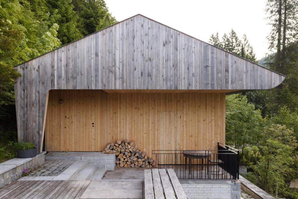 un edificio de madera con una pila de leña en Urfeld26 Walchensee Berghaus mit Sauna, en Urfeld