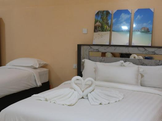 twee zwanen zitten bovenop twee bedden bij Tropical stay Thulusdhoo in Thulusdhoo