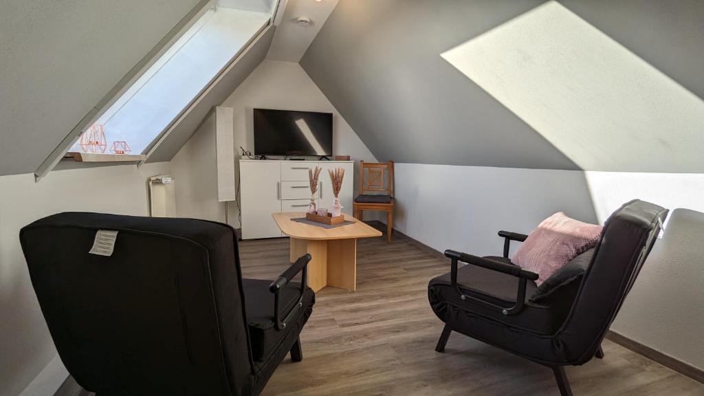 a attic room with two chairs and a table at Dachgeschosswohnung mit Pool in Nordleda