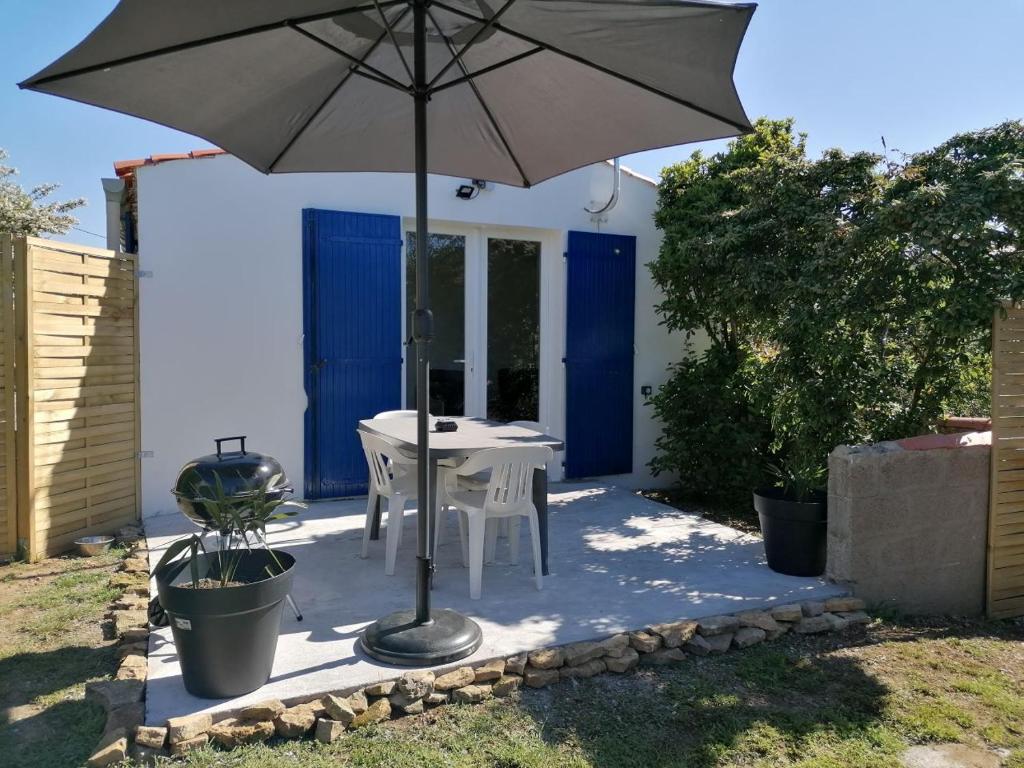 patio ze stołem i parasolem w obiekcie Maison 3 personnes dans village atypique w mieście Talmont-sur-Gironde