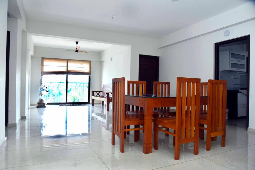uma sala de jantar com uma mesa de madeira e cadeiras em Krishna Dhwani Apartments em Tellicherry