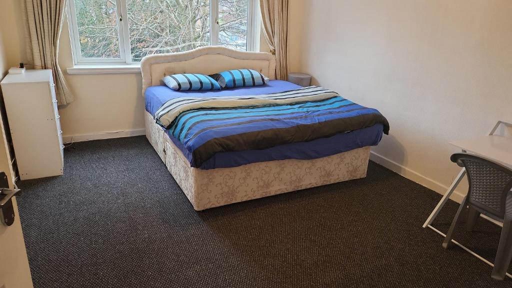Tettenhall的住宿－Masters bedroom in a 3 bedroom house，一间卧室配有一张带蓝色床单的床和一扇窗户。