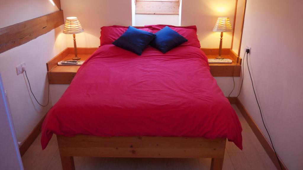 a bedroom with a red bed with two night stands at Hobkin Holiday Cottages in Broughton in Furness