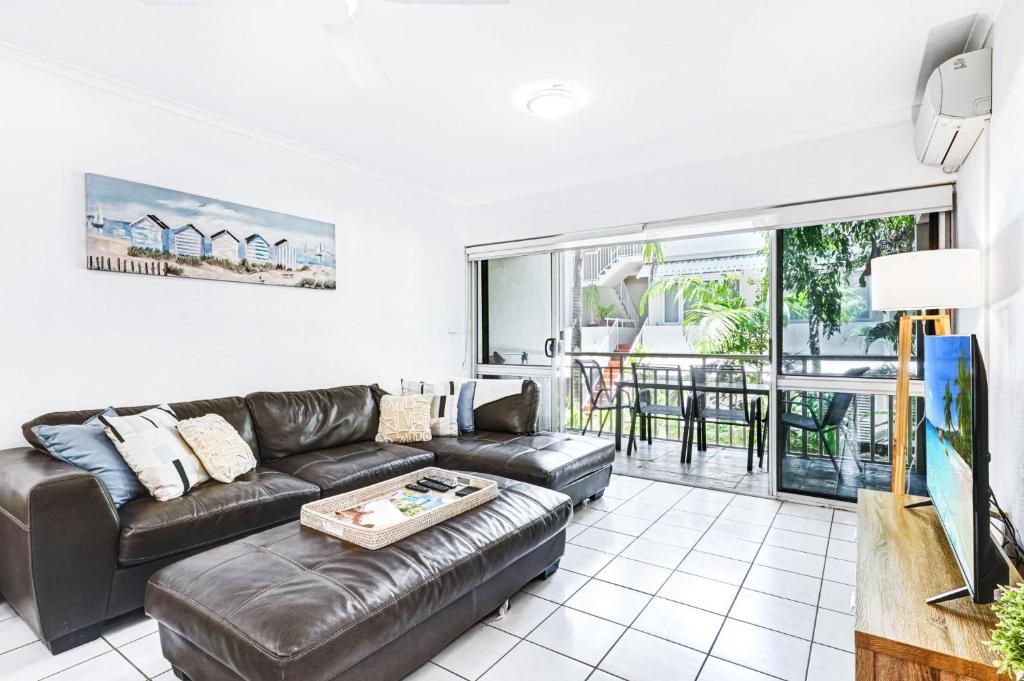 a living room with a leather couch and a balcony at Cozie Homes - Mantaray on Macrossan in Port Douglas