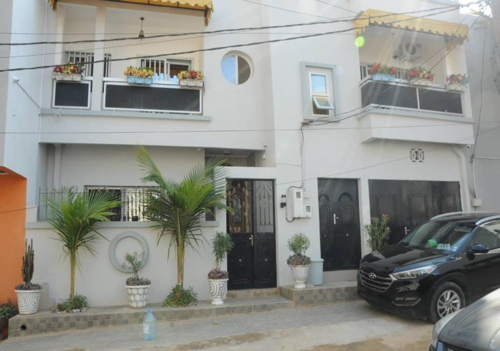 a black car parked in front of a white building at Résidence Doux in Dakar
