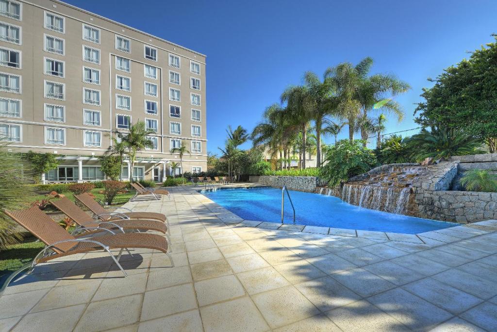 a hotel with chairs and a pool in front of a building at Hotel Deville Prime Porto Alegre in Porto Alegre