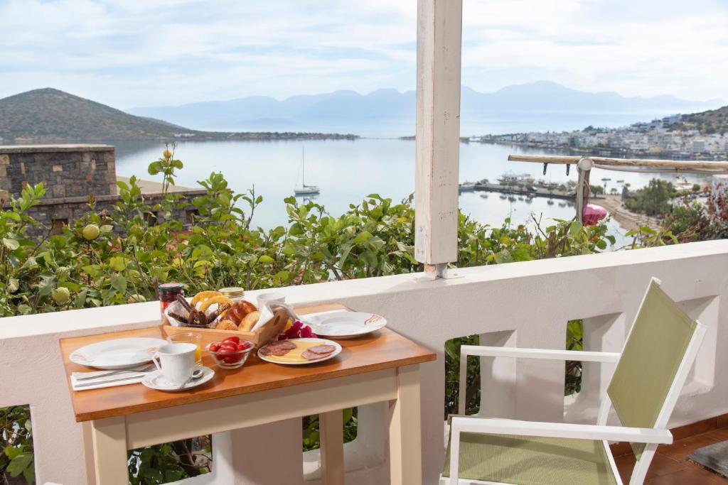 a table with food on a balcony with a view of the water at Elounda Summer Apt in Elounda