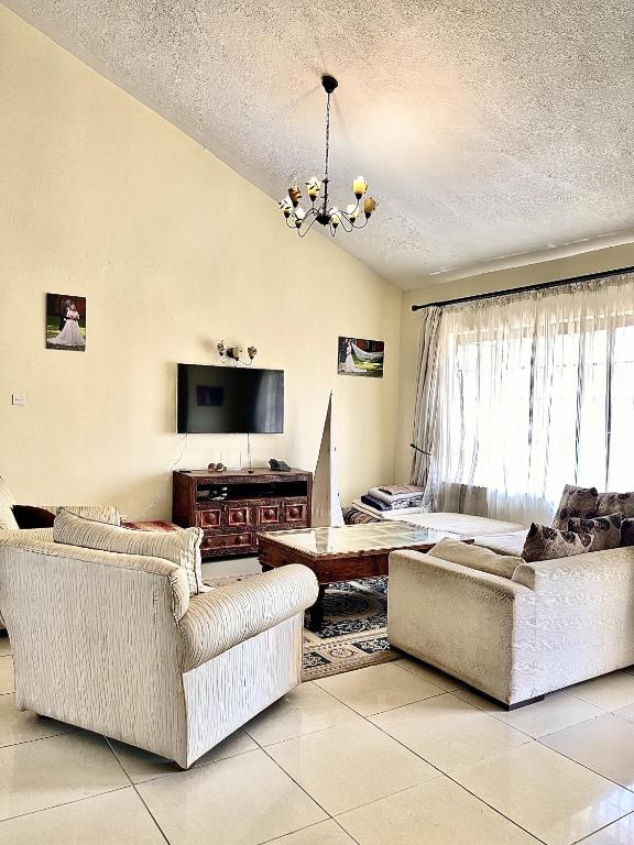 uma sala de estar com dois sofás e uma televisão em Westlands Escape-Homestay em Nairobi