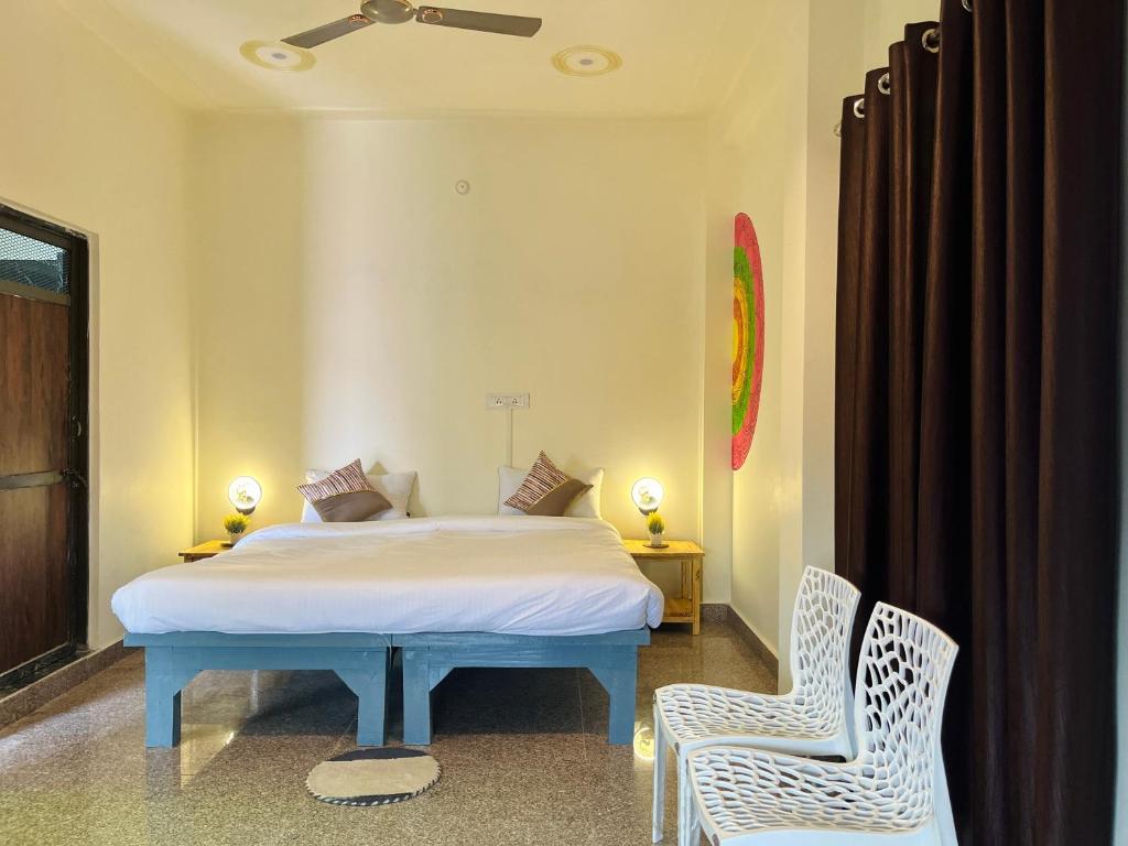 um quarto com uma cama e 2 cadeiras em Kashi Village Home Stay em Varanasi