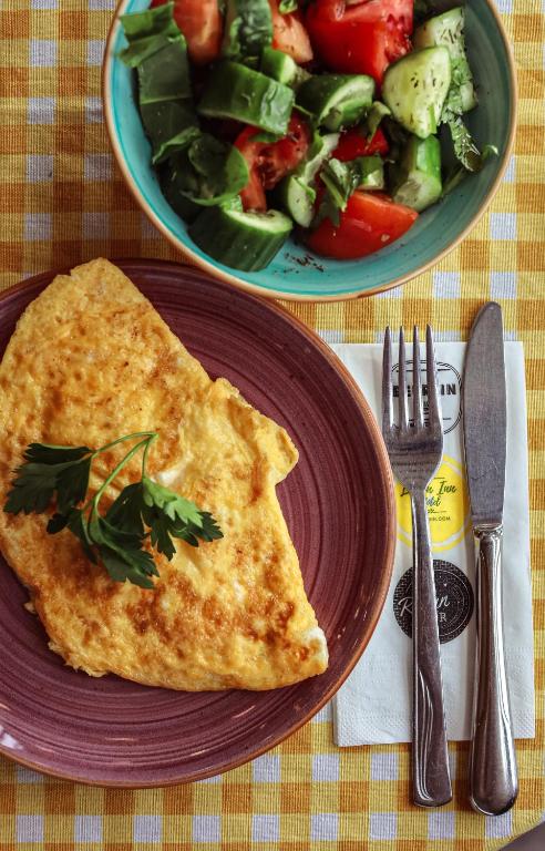a plate with a omelet and a bowl of salad at Limon Inn Hotel, Taşucu in Tasucu