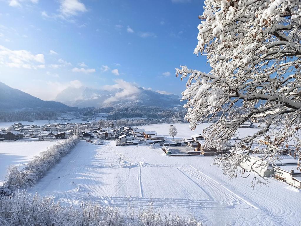 a village covered in snow with mountains in the background at Apartment Sonnenwinkl in Kössen