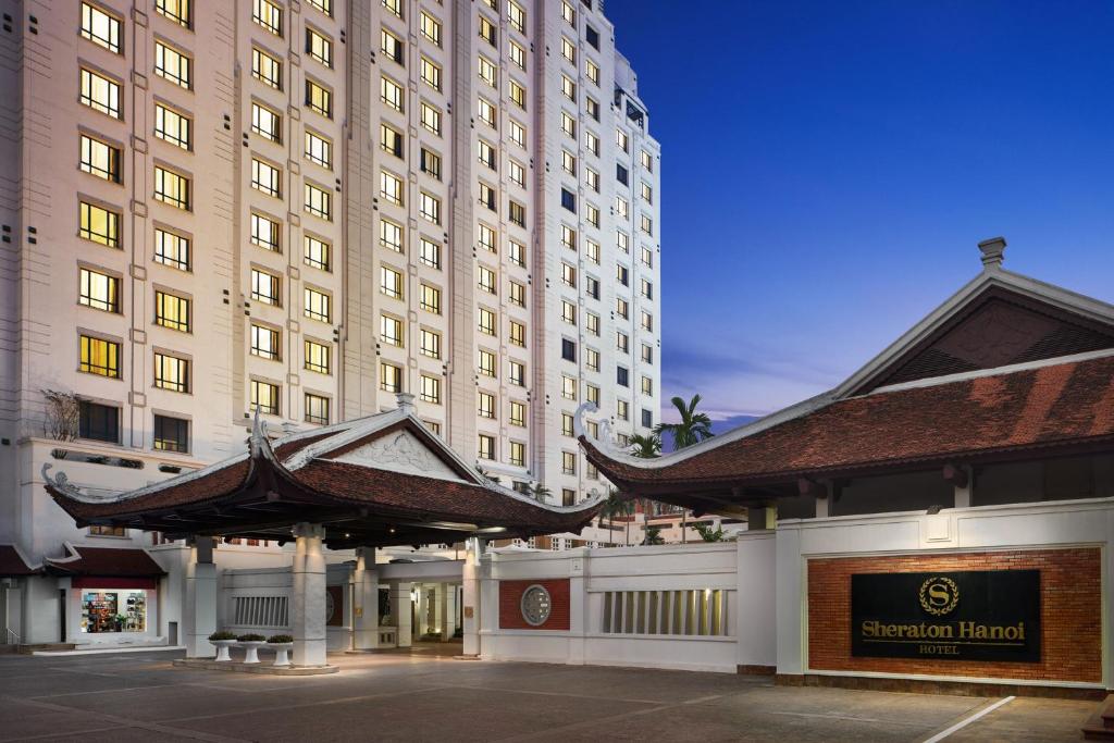 a large building next to a street with buildings at Sheraton Hanoi Hotel in Hanoi