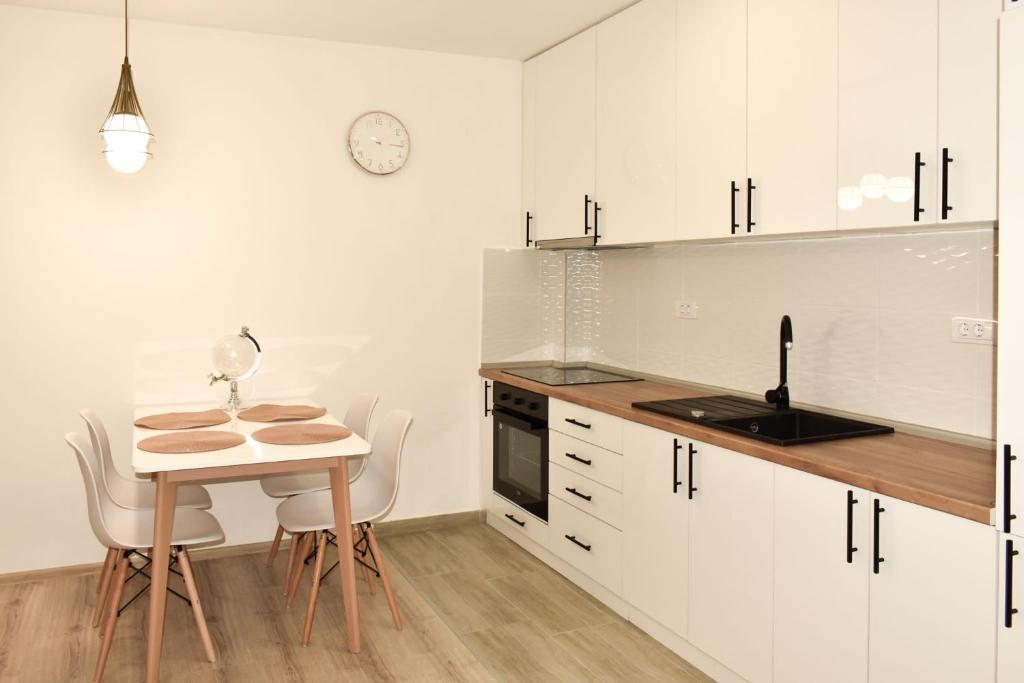 eine Küche mit weißen Schränken sowie einem Tisch und Stühlen in der Unterkunft Apartman Biser 4 in Ruma