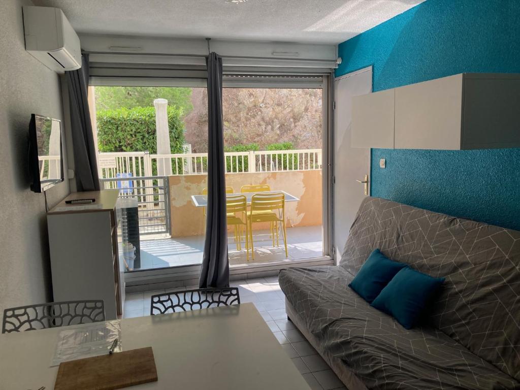 a living room with a couch and a view of a patio at Appartement T2 climatisé 4 personnes piscine et parking privée in Sète