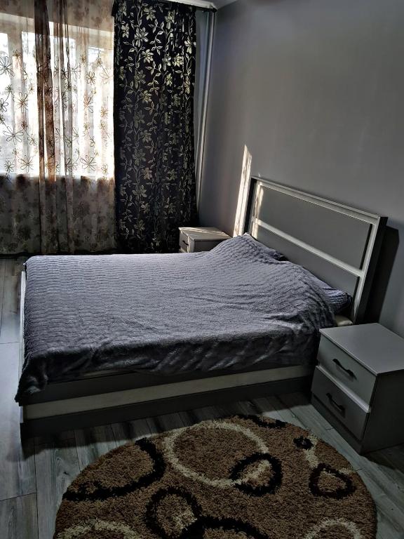 a bedroom with a bed with a rug and a window at Алматы квартира. 31 in Almaty