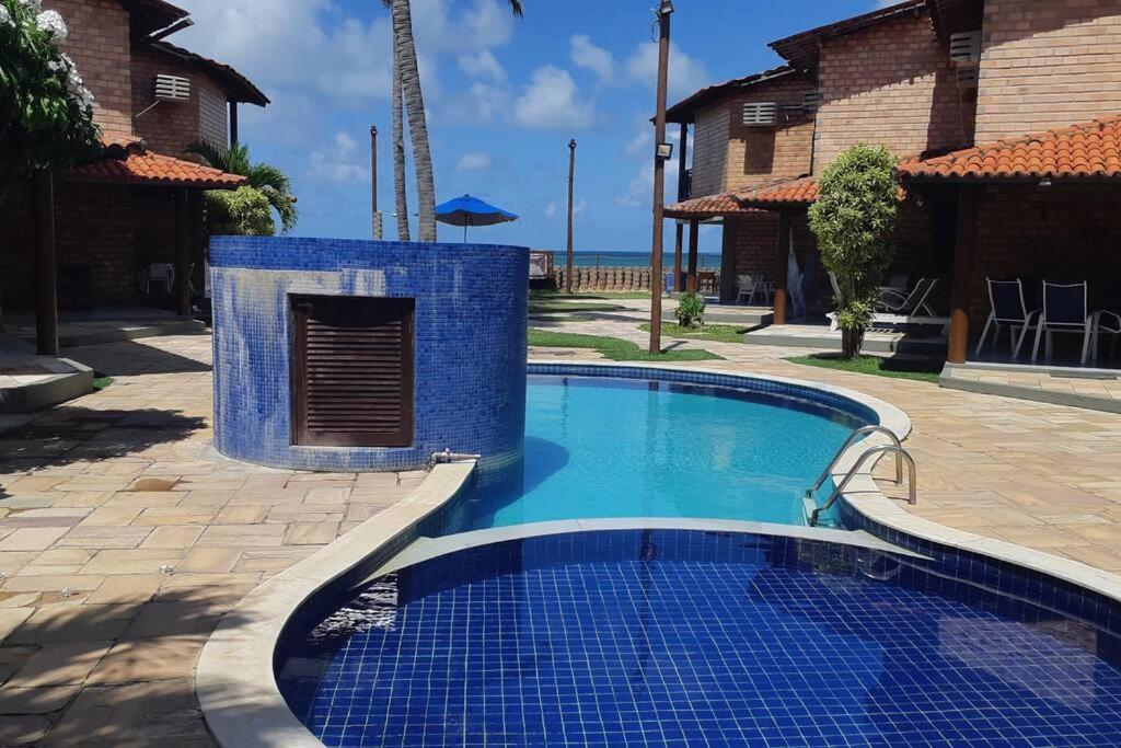 einem Pool mit blauen Fliesen vor einem Haus in der Unterkunft Chalé Pé na Areia, Cond. Beira Mar, Maragogí/AL in Maragogi