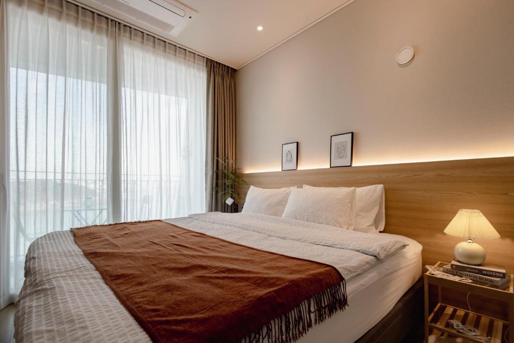 1 dormitorio con 1 cama grande y ventana grande en 영종도 구읍뱃터 오션뷰-Luxe 베드,넷플릭스, 사운드바, 식물테리어, 무료주차, en Incheon