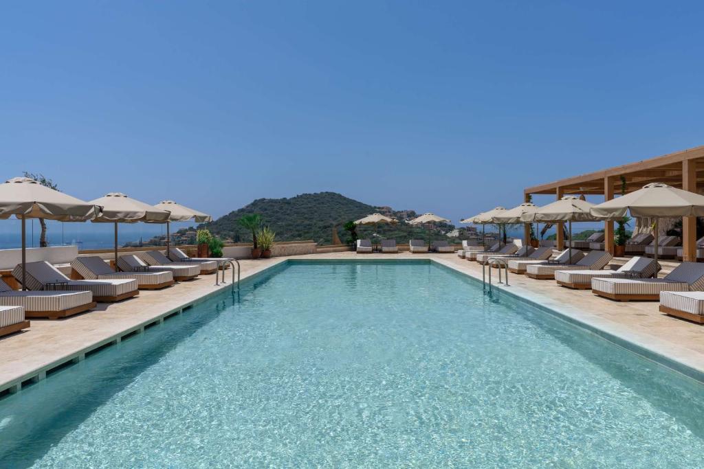 a swimming pool with chairs and umbrellas at Radisson Blu Hotel, Kas in Kaş