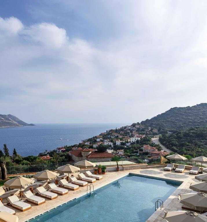 a pool with chairs and umbrellas and the ocean at Radisson Blu Hotel, Kas in Kaş