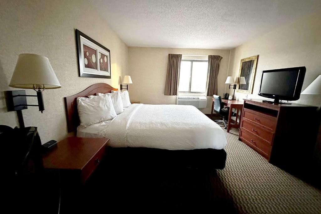 a hotel room with a bed and a flat screen tv at Travelodge by Wyndham Rapid City - Black Hills in Rapid City
