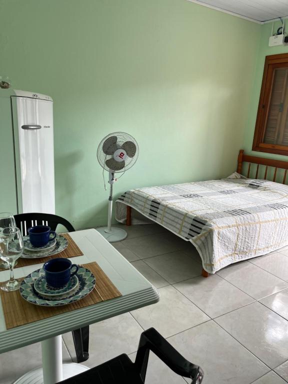 Zimmer mit einem Tisch, einem Bett und einem Ventilator in der Unterkunft Apartamentos Pura Vida em Atlântida Sul in Xangri-lá