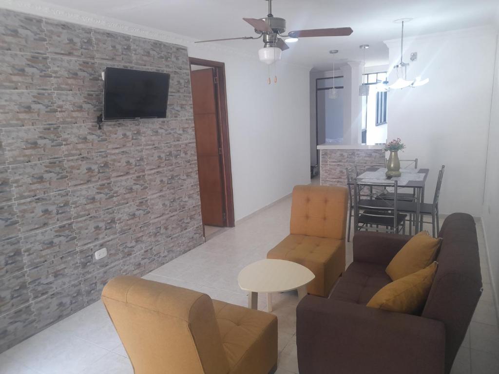 salon z kanapą i telewizorem na murze z cegły w obiekcie Alojamiento turístico Paula Viktoria w mieście Villavicencio