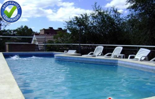 una piscina con sillas blancas y una piscina en Terrazas del Diquecito en Villa Carlos Paz