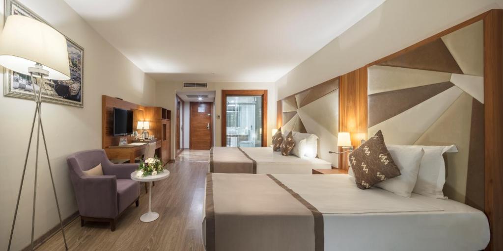 ein Hotelzimmer mit 2 Betten und einem Wohnzimmer in der Unterkunft Nirvana Mediterranean Excellence - Ultra All Inclusive in Beldibi