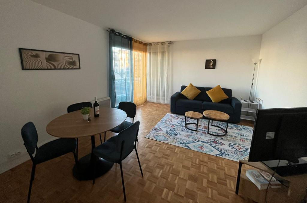 uma sala de estar com uma mesa e um sofá em Bel appartement à 9 minutes de Paris em Bois-Colombes