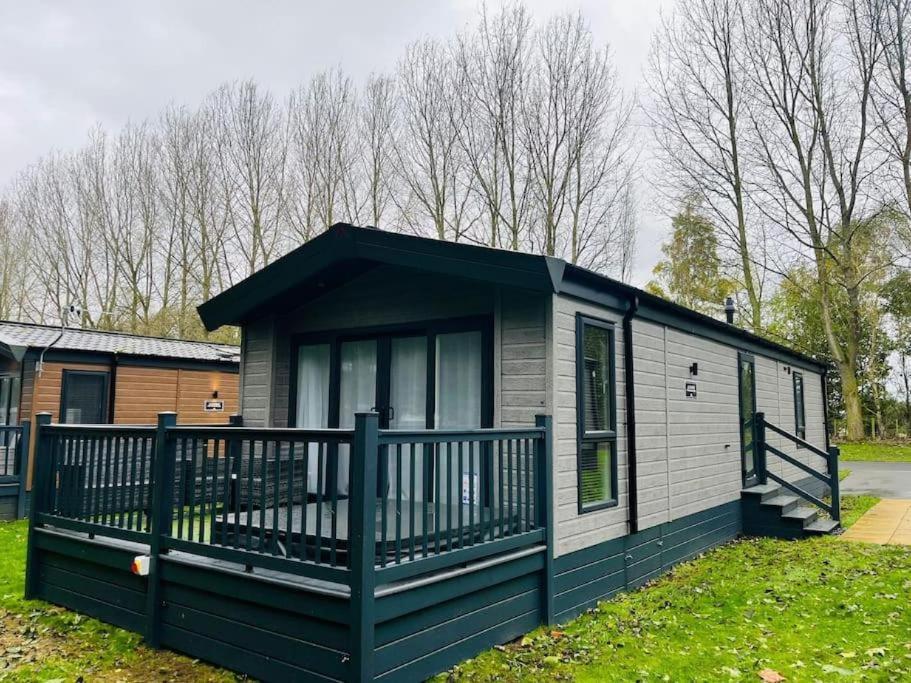 a black and white tiny house with a porch at Wag Tail Lodge with Hot Tub in Barmby on the Moor
