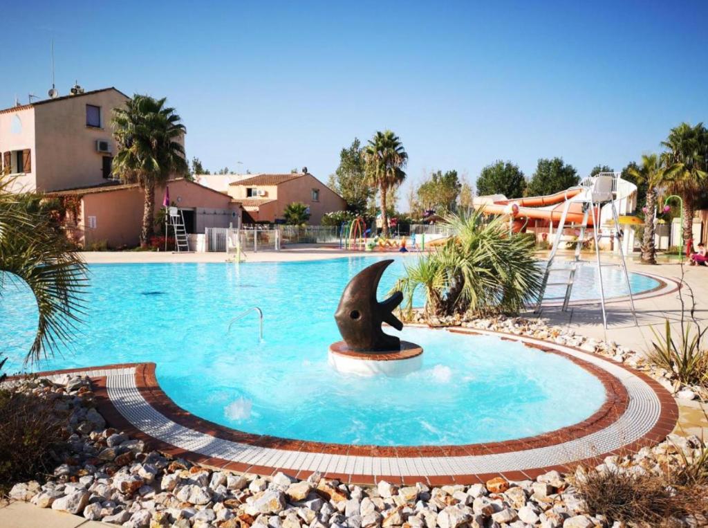 a dolphin fountain in the middle of a swimming pool at Camping Sable du Midi MH 6-8 personnes in Valras-Plage