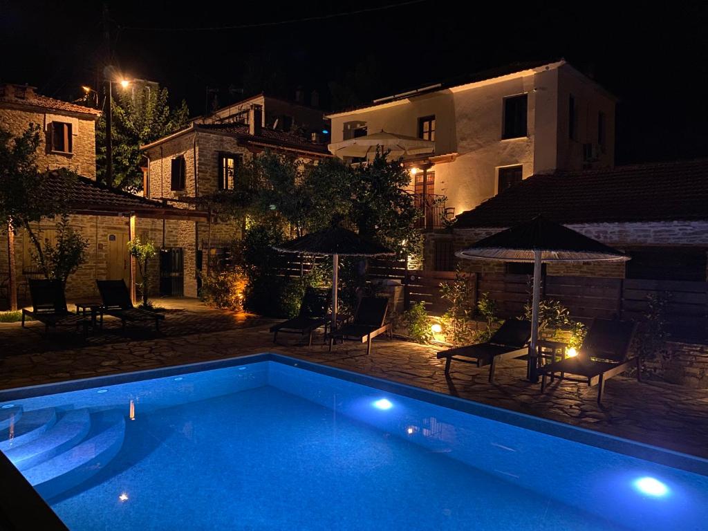 una piscina con sillas y sombrillas por la noche en Xinovrissi Apts & Pool, en Xinóvrisi