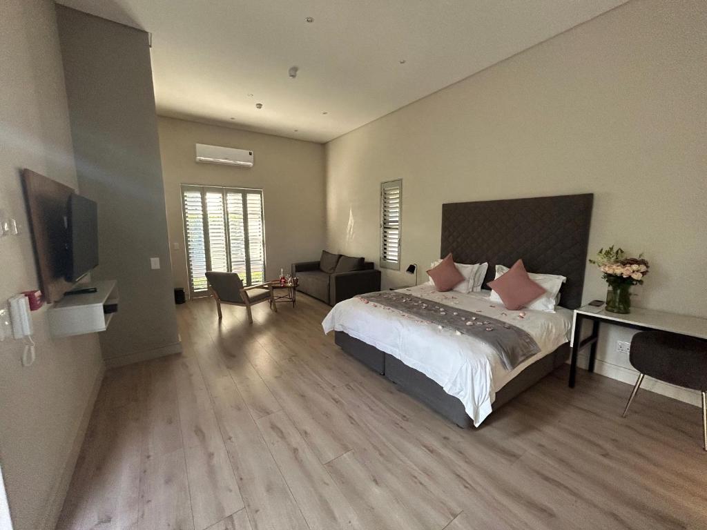 Dormitorio con cama, escritorio y TV en The Wantage Suites en Johannesburgo